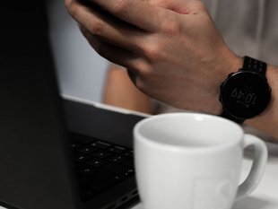 Imagebild mit Person die Smartphone bedient und vor einem Laptop sitzt. Daneben steht eine SIWA Kaffee Tasse